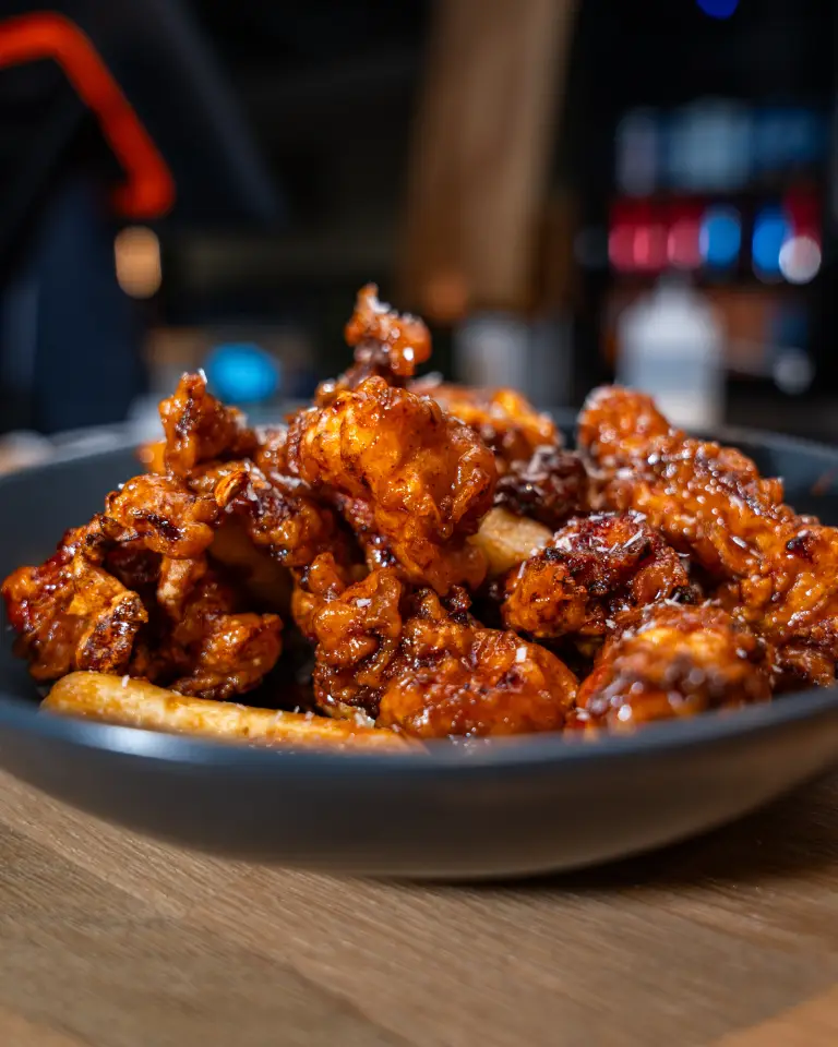Würzig gebratenes Hähnchen in schwarzer Schüssel, serviert in der Markthalle im Königshof Essen.